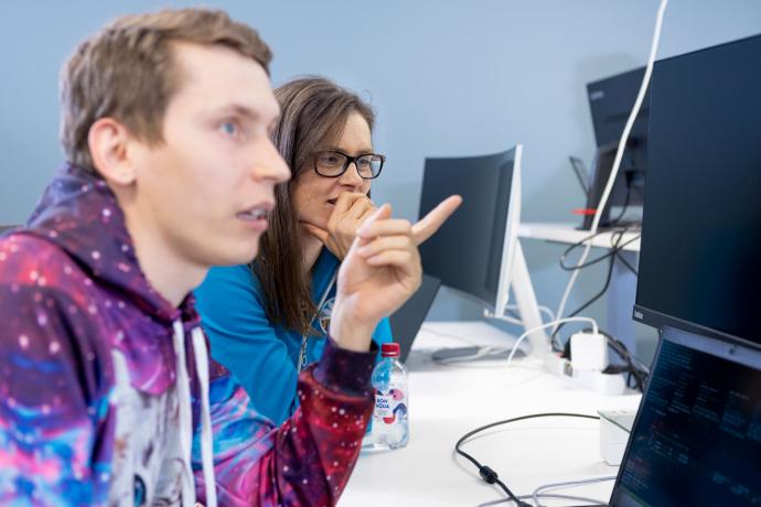 Kaksi työntekijää saman näytön äärellä tekemässä yhteistä projektia